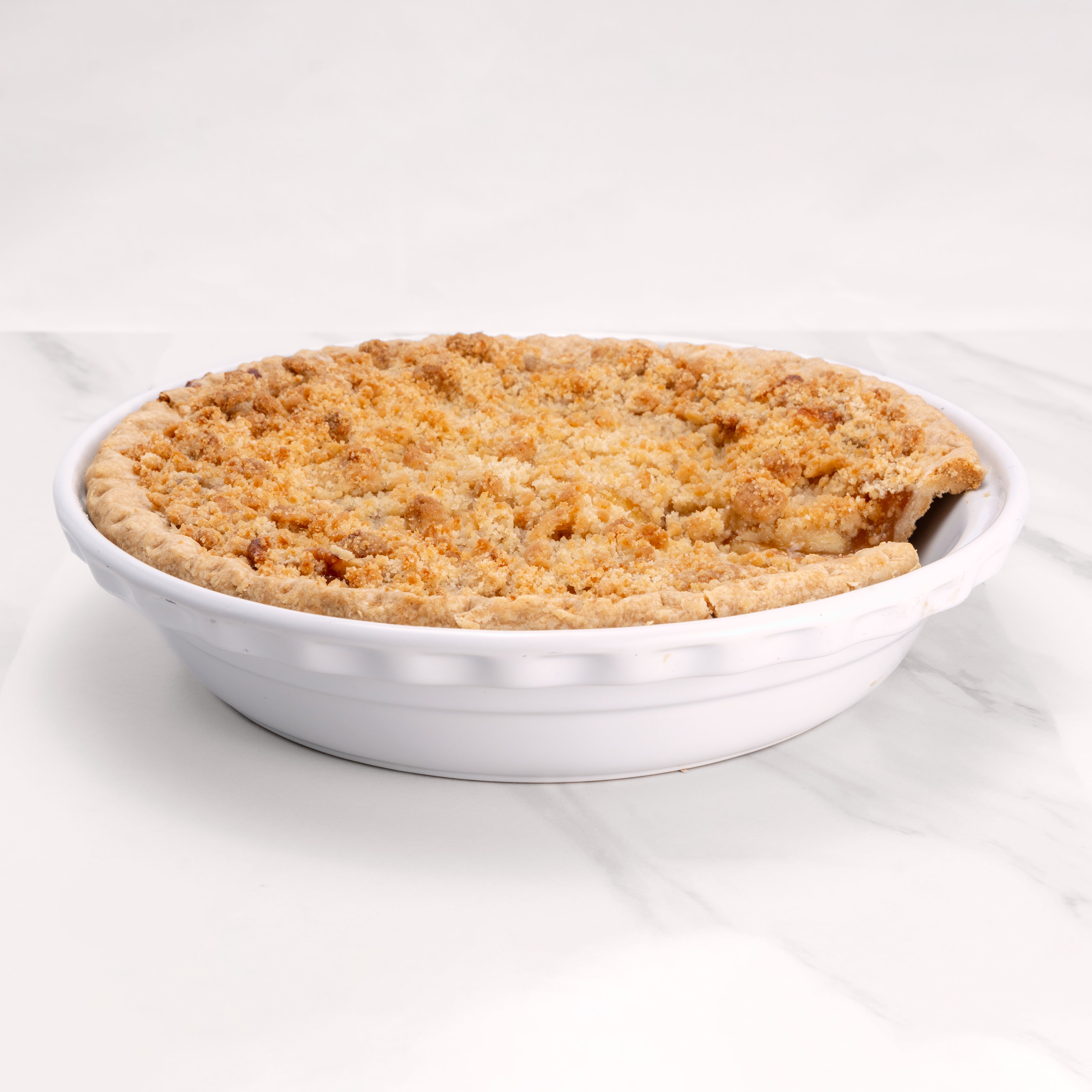 11" Gluten Free Apple Crumb pie in white pie dish with slice missing.