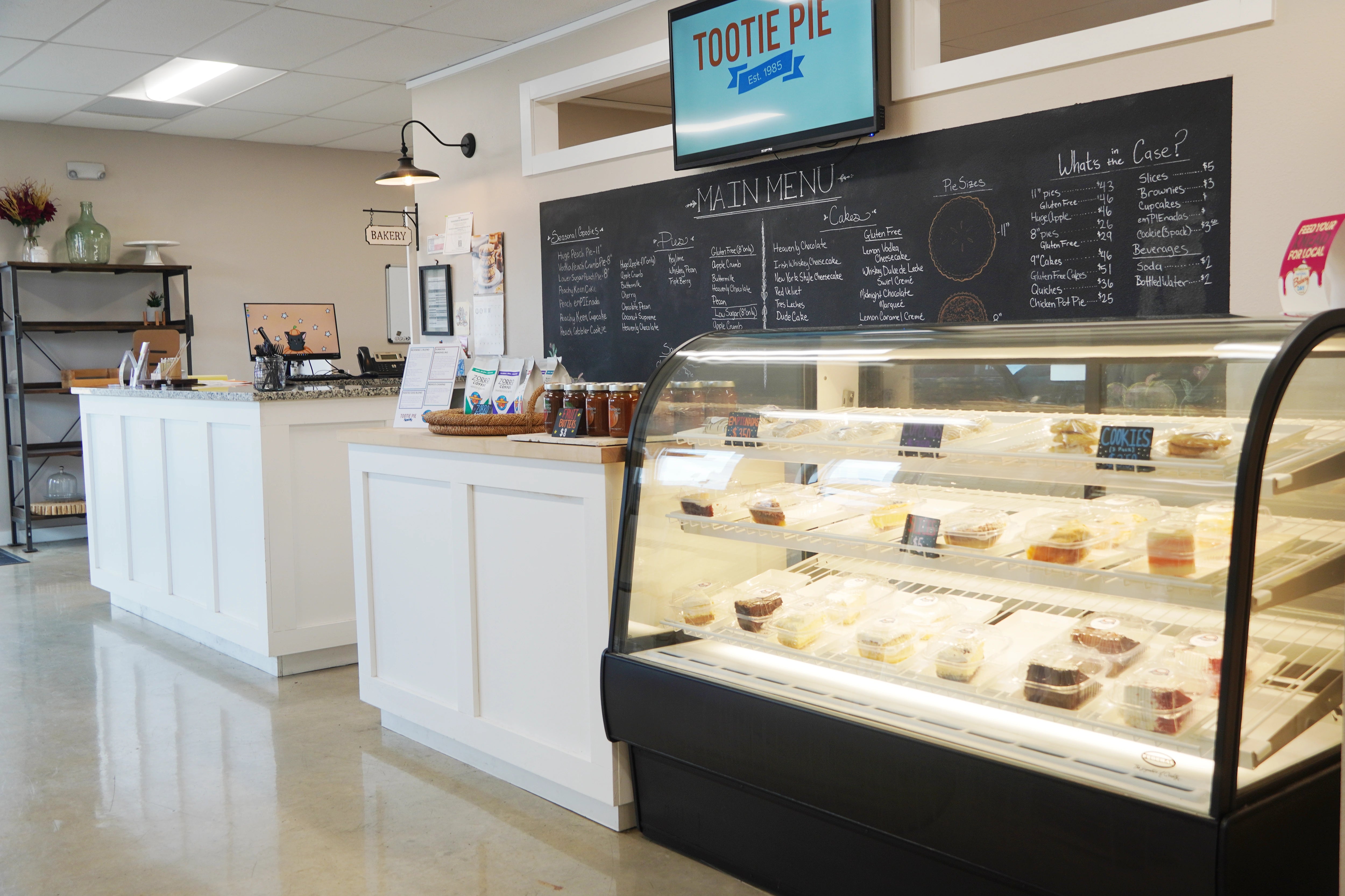 Interior of store showing various products such as coffee, cake slices, and fruit butter.