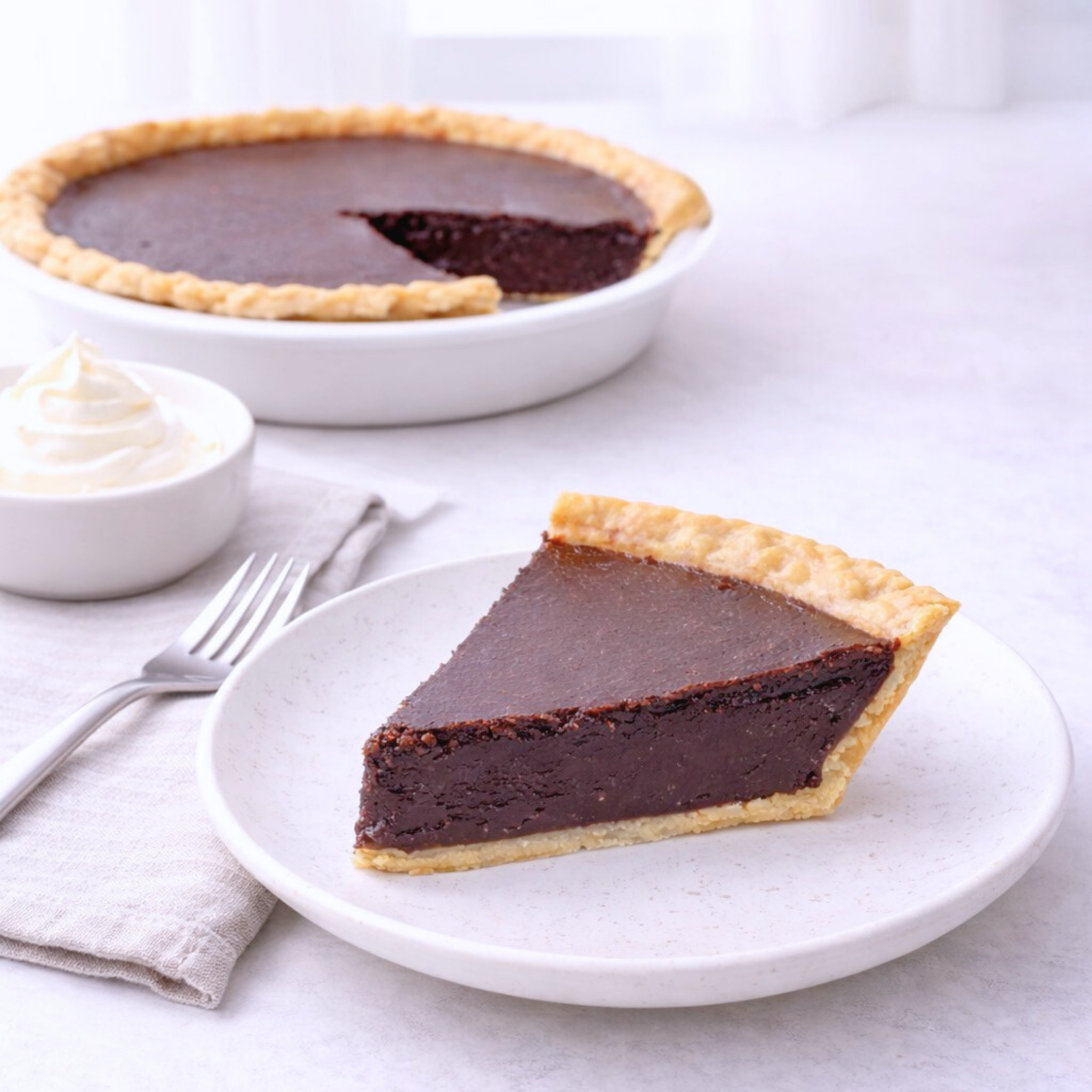 No sugar added Chocolate pie with a slice on a plate, accompanied by whipped cream.