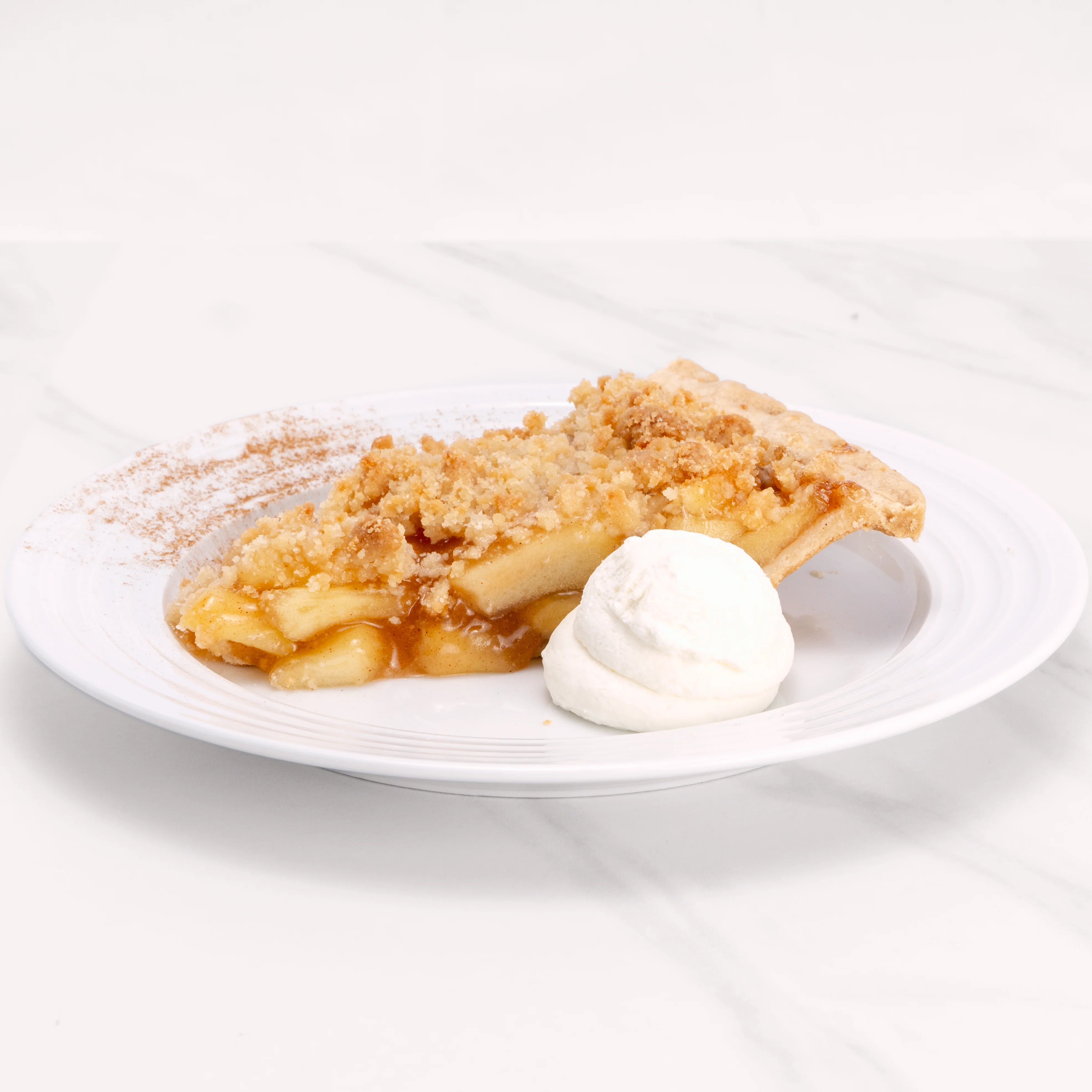 Slice of Apple Crumb Pie garnished with cinnamon and a dollop of crème.
