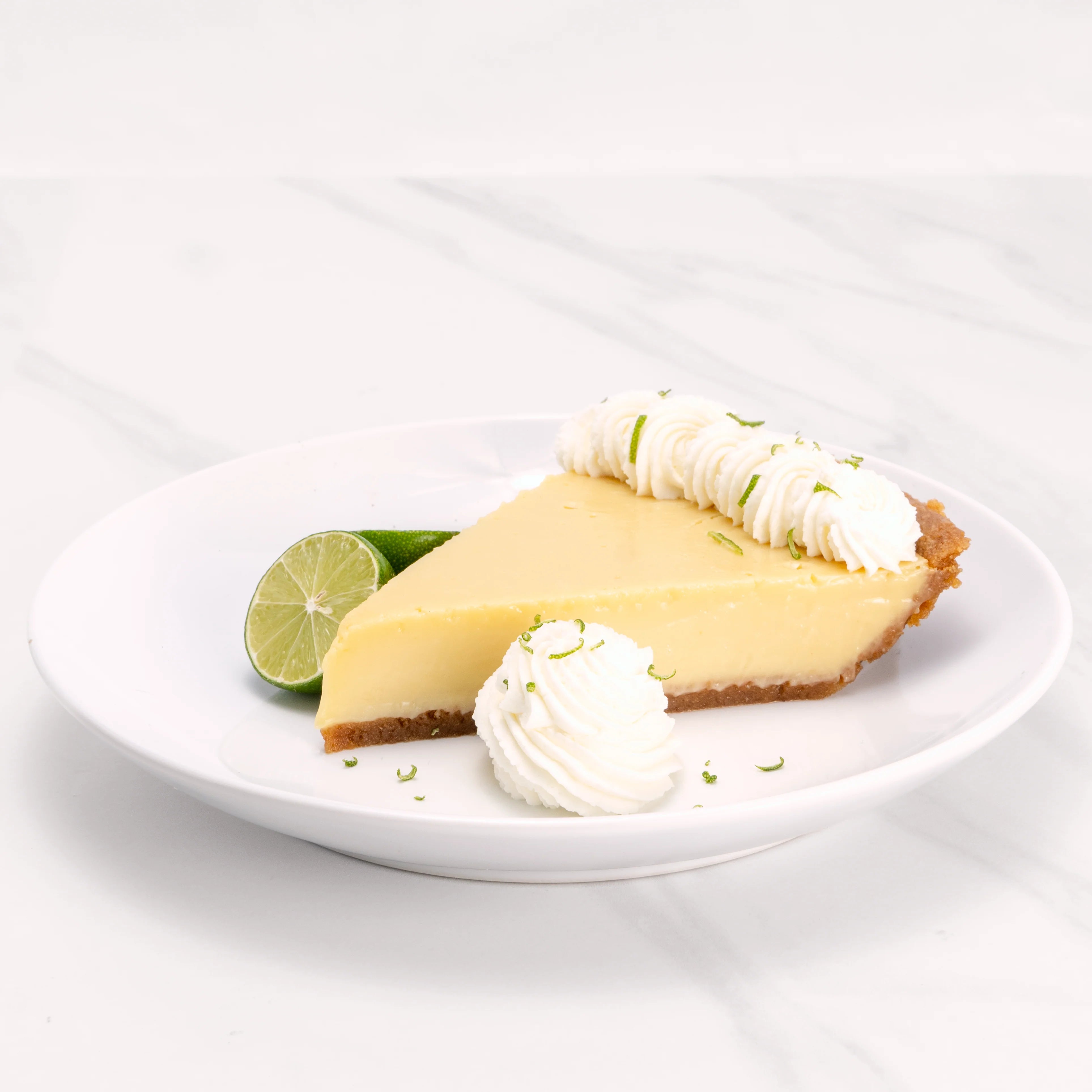 Slice of Key Lime Pie garnished with lime and a dollop of crème.