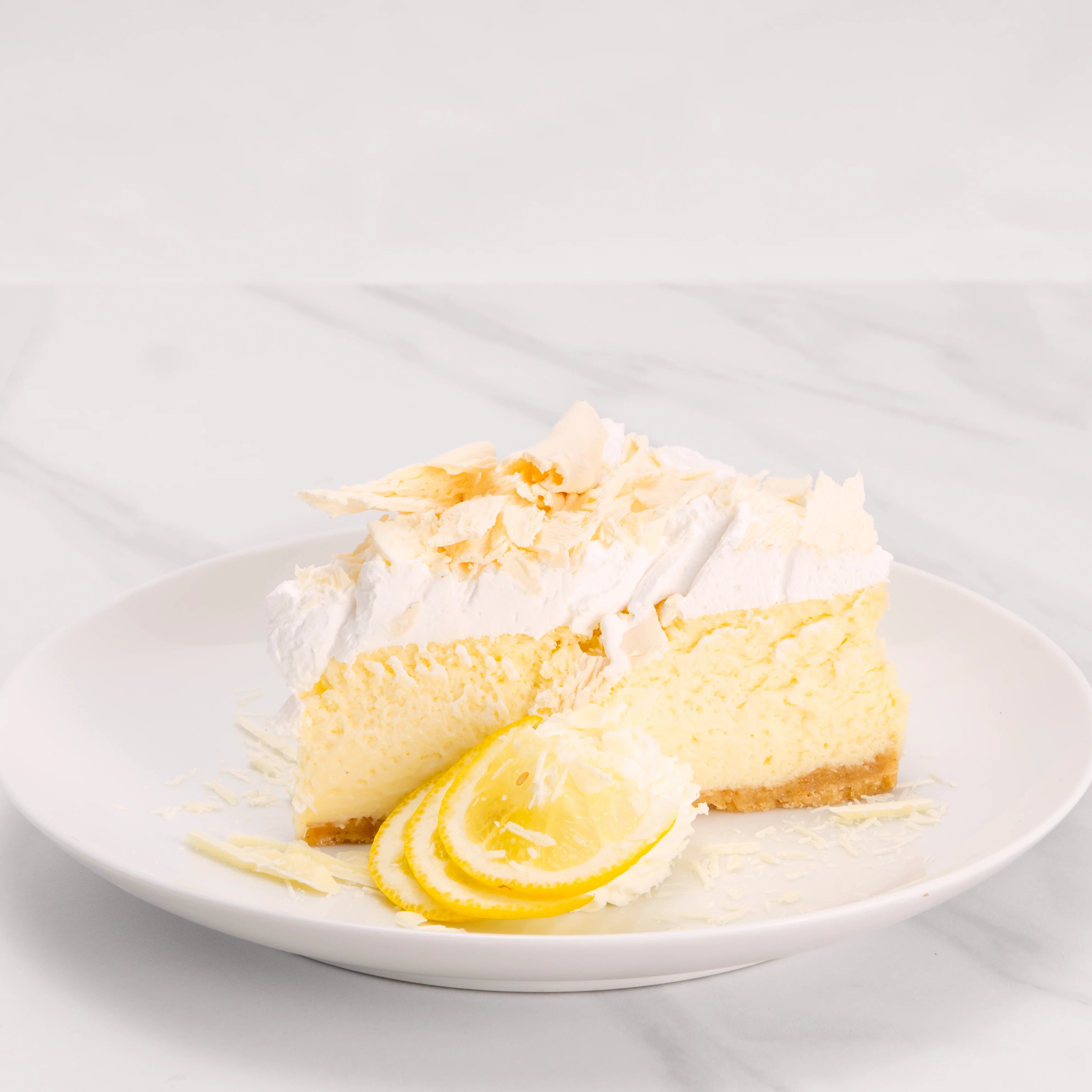 Slice of Gluten Free White Chocolate Crème Cake garnished with lime, white chocolate, and a dollop of crème.