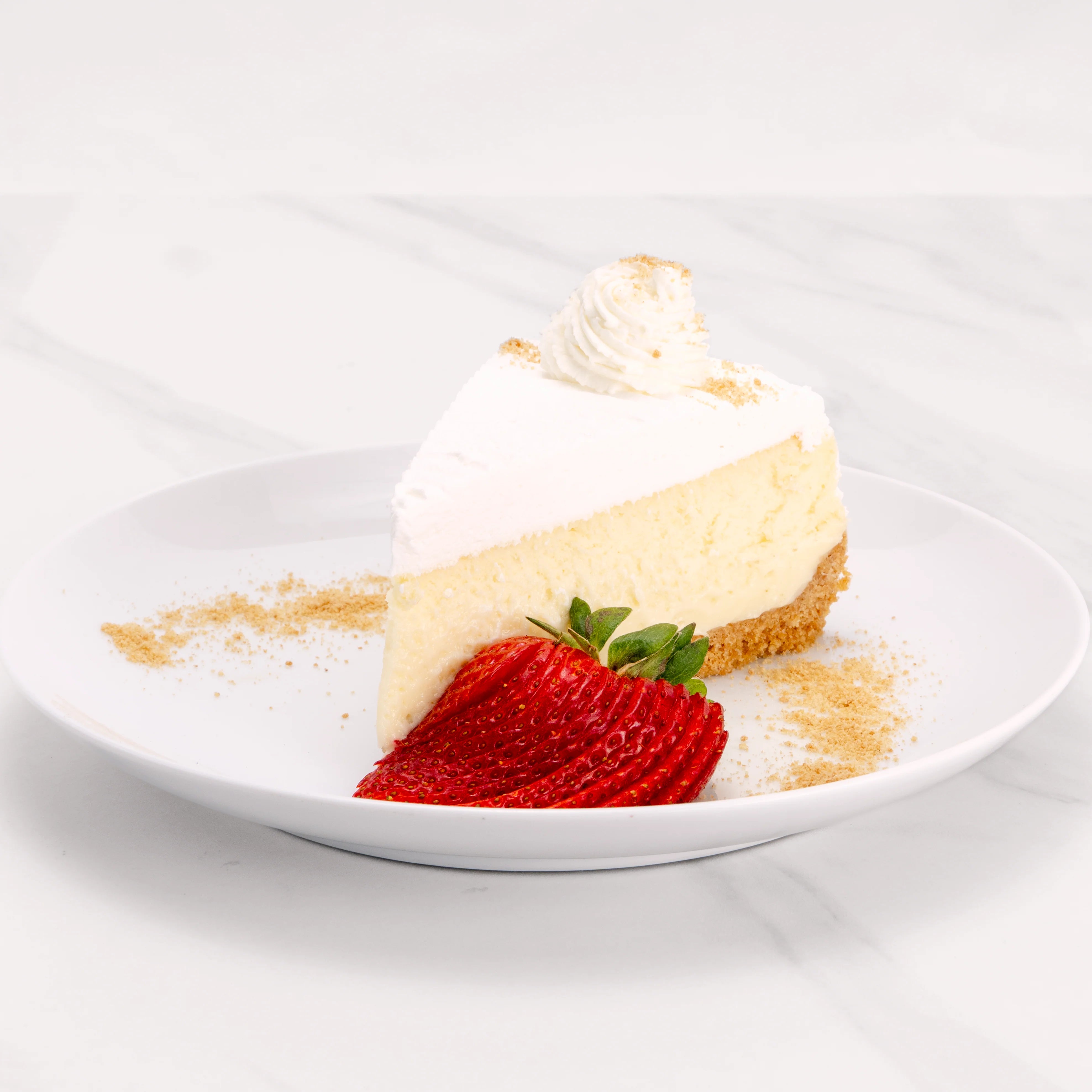 Slice of New York Cheesecake garnished with strawberries and sable.