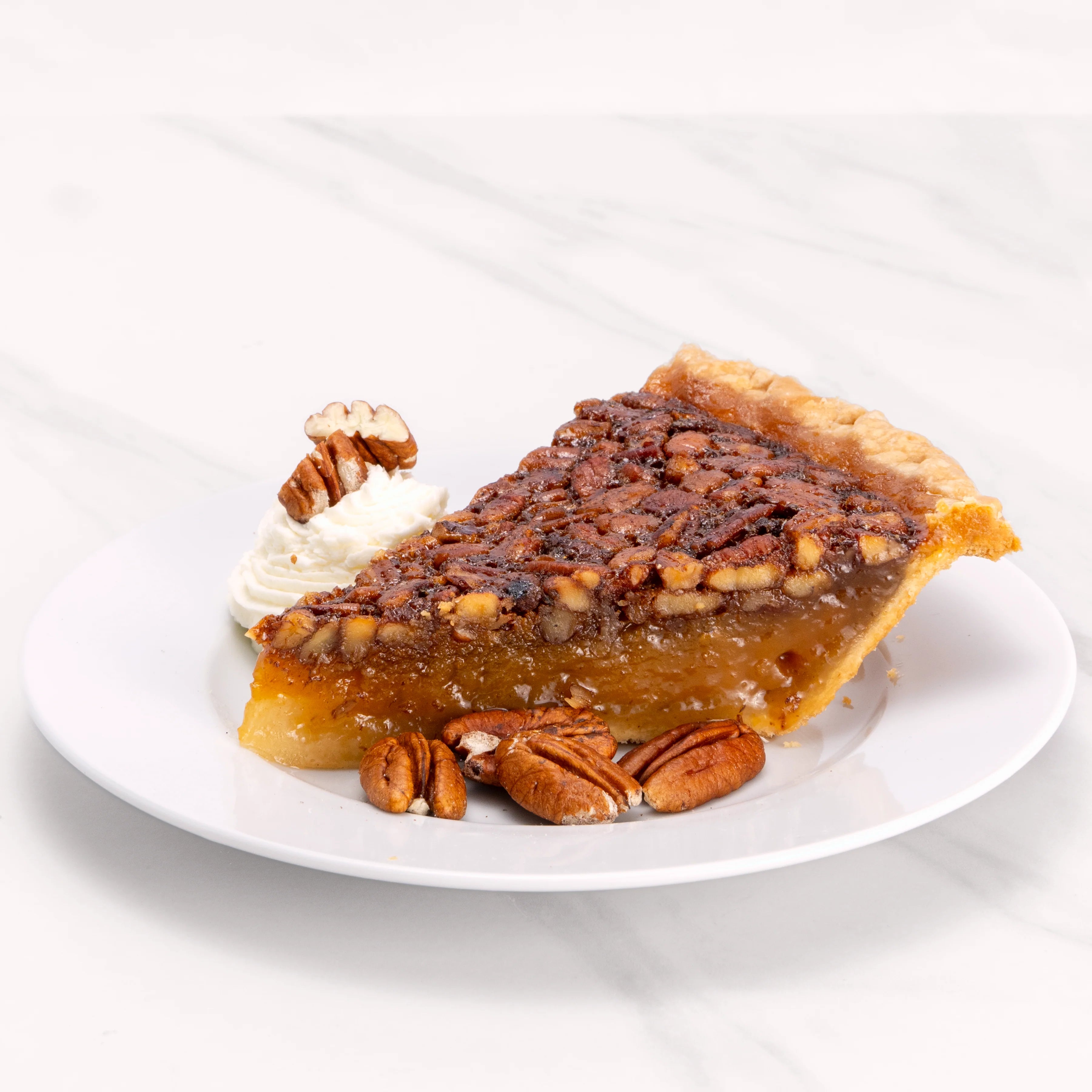Slice of Pecan Pie garnished with pecans and crème.